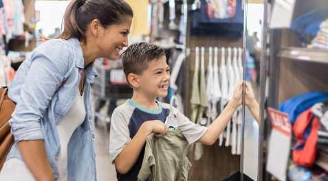 A mom and son shopping for clothes at a supermarket.