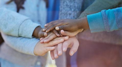 A closeup of a group of kids stacking their hands in unity.