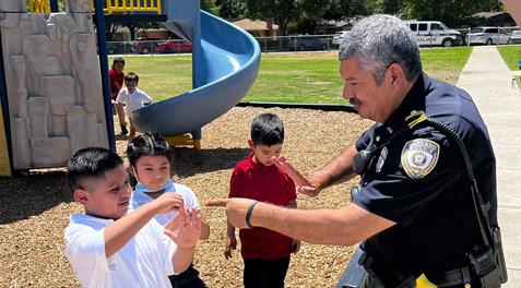 An officer playing with three young kids on a school playground.