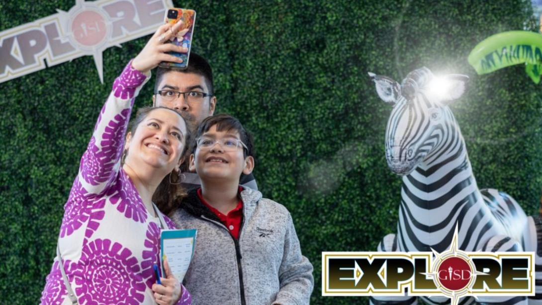 family taking a selfie in front of a safari themed backdrop with a zebra.