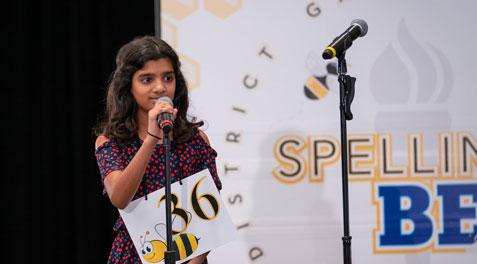 A student sounding out a word into a microphone at the district Spelling Bee.