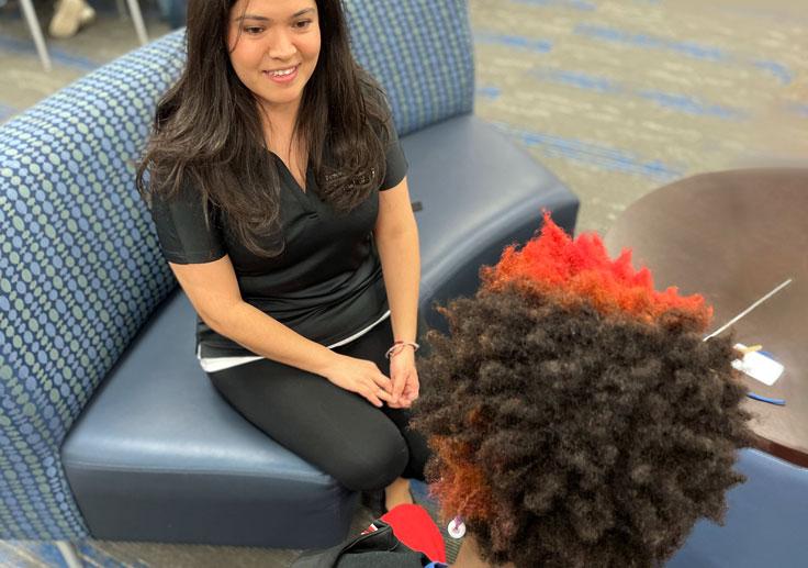 A responsive services counselor smiling gently as she sits and talks to a student in a community room.