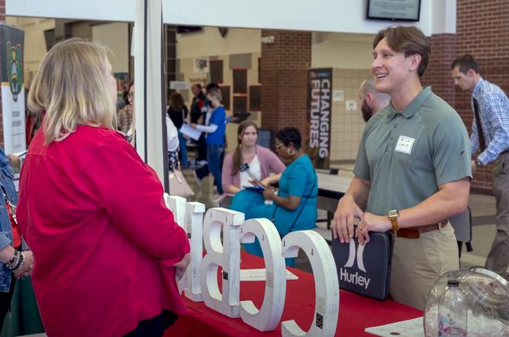 An applicant talking to an elementary school admin during a job fair.