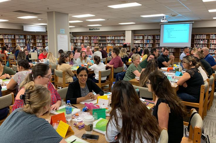 Teachers discussing learning in a large new teacher training session.