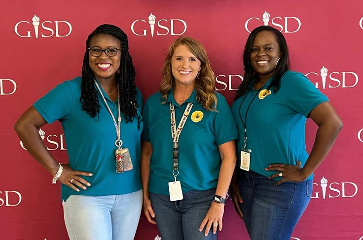 The Professional Development Steam posing together and smiling while wearing polos with their department logo.