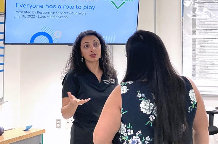 Staff presenter answering question of another staff member with a screen in the background that says "Everyone has a role to play."