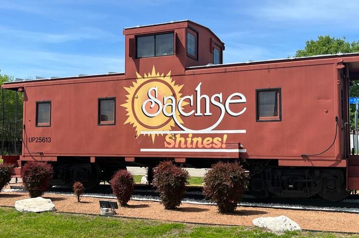 A bright red stationary train car reading "Sachse shines!"