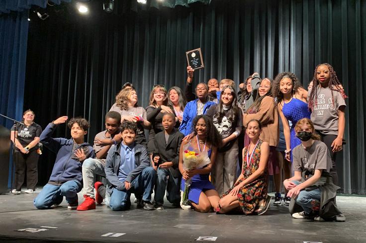 The middle school actors of "Chime In" posing on stage with their plaque.