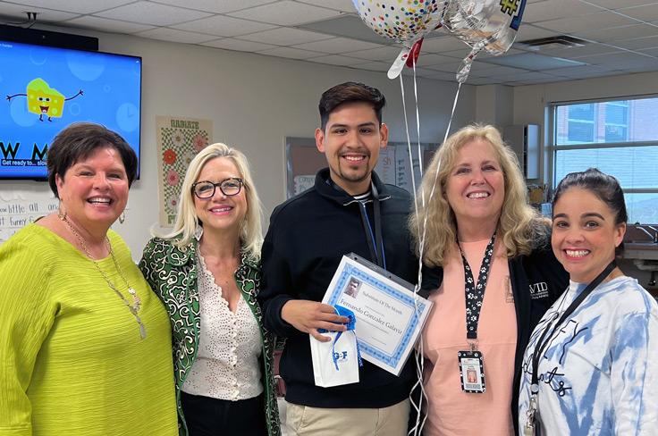 Staff members smiling with a substitute of the month who received a gift, certificate and balloons from GISD staff.