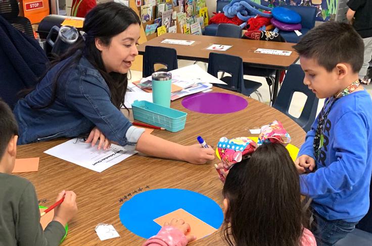 A teacher working with a small group of students on an activity.