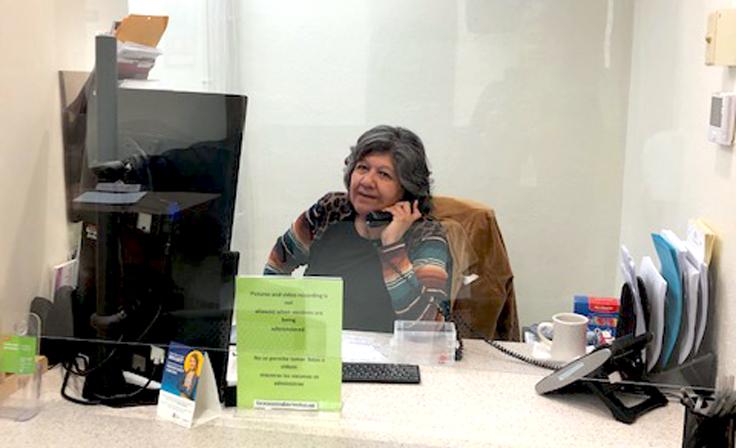 An employee at the Student Services Clinic smiles while taking a call at her desk.