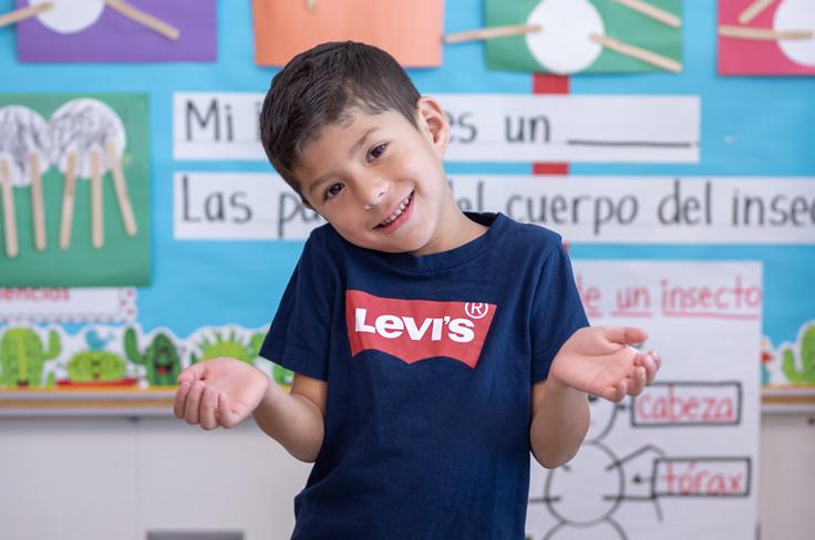 A young student smiling and shrugging, as if confused.