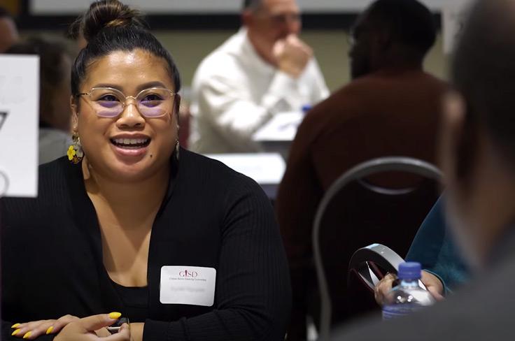 A community member speaking to other people at her table during committee meeting.