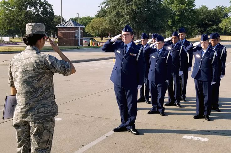 An army officer returning salute to a group of uniformed AFJROTC students.