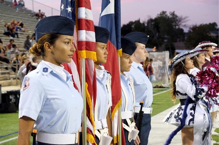 AFJROTC students standing at attention while holding the U.S. and Texas flag at a football game.