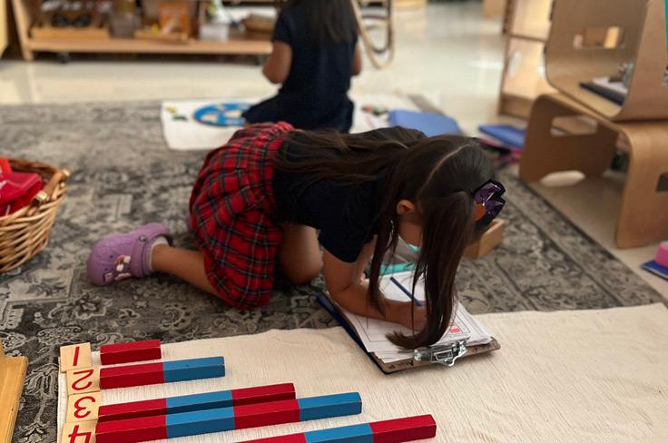 A girl in Montessori using blocks to count and write her conclusions.