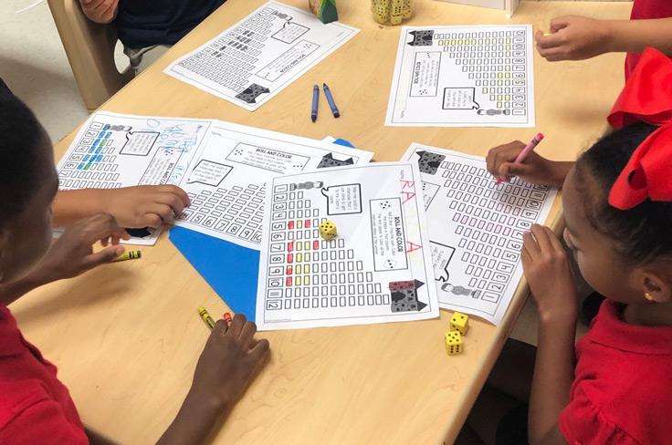 A group of students working together with dice at a Montessori math station.