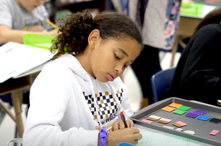 A Dyslexia student writing while using colored blocks to visualize breaking down parts of words.