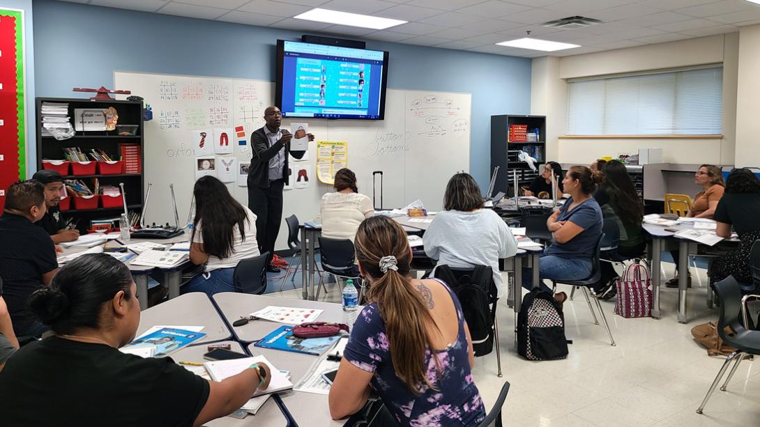 A teacher showing a class of adults a picture of a bag with the English translation printed on it.