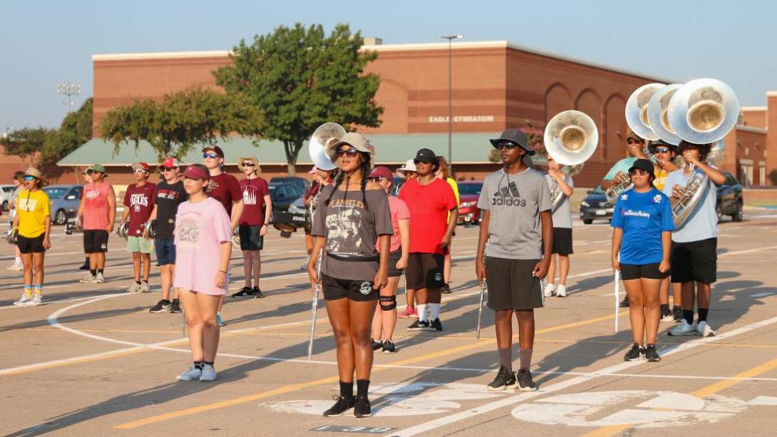 Students stand in marching band formation with instruments