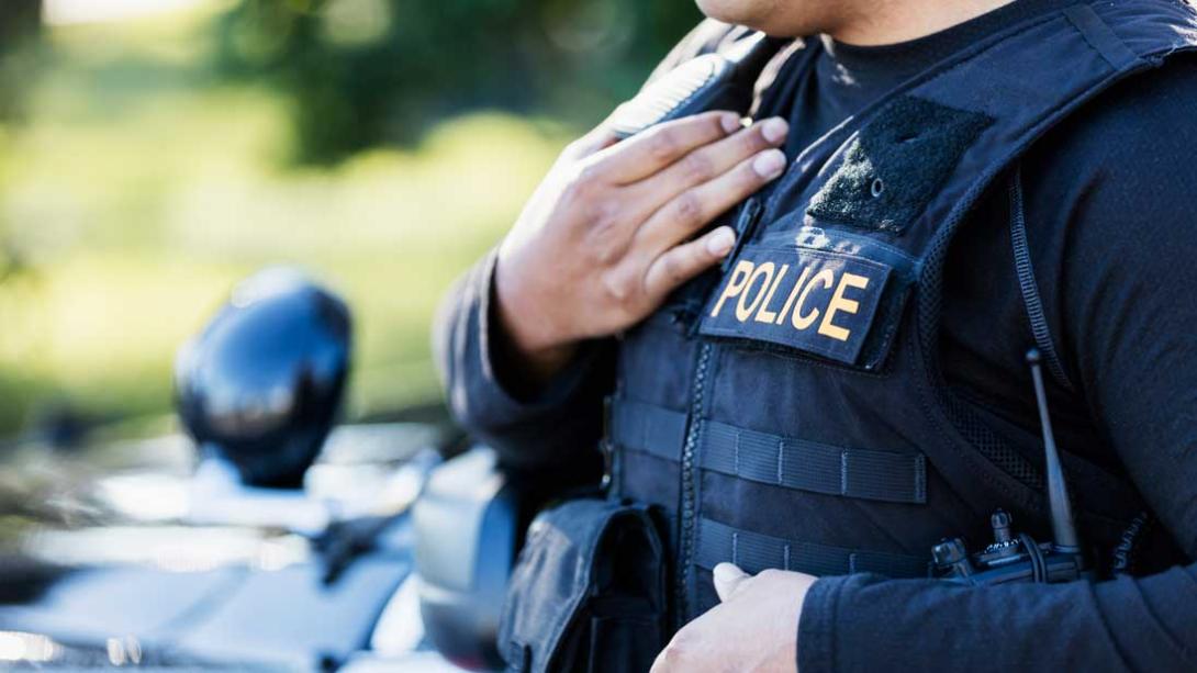 close up of police officer's uniform where his hand is next to the word police on his vest