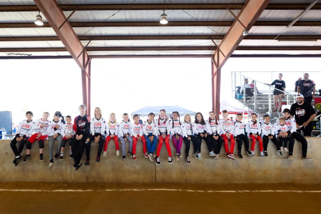 members of the L.O.V.E. racing team sit on a ledge