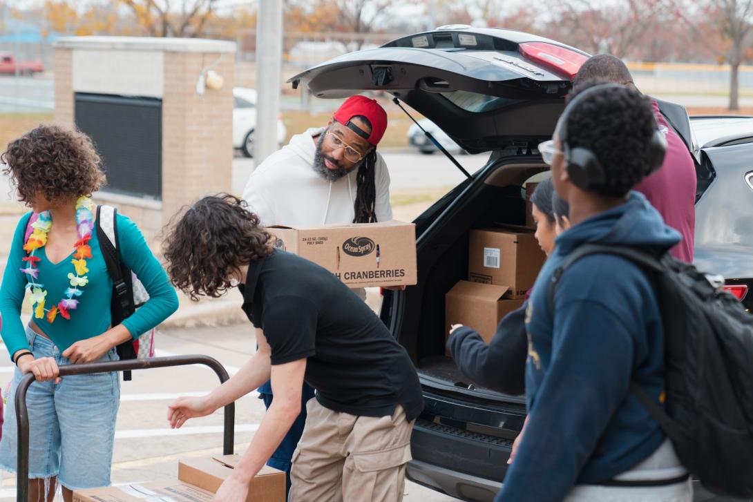 Adults and students unload food boxes