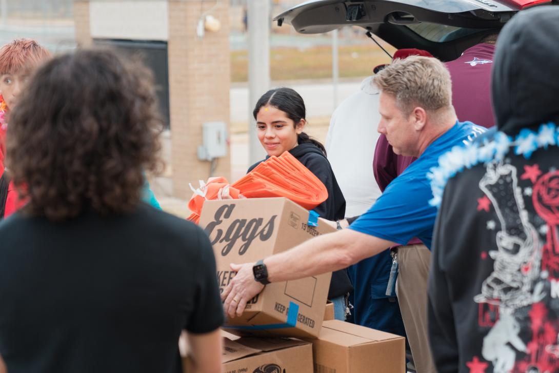 Adults and students unload food boxes