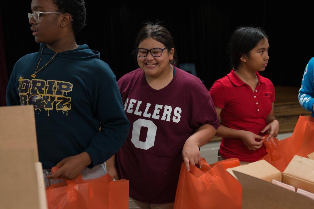 Female student smiles as she loads food into bags