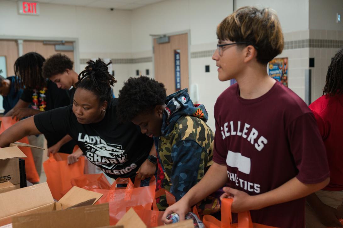 Students and staff form an assembly line to pack food into bags