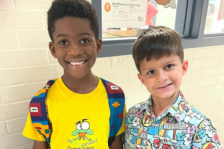 Two boys smiling. One has his head tilted in a quizzical manner.