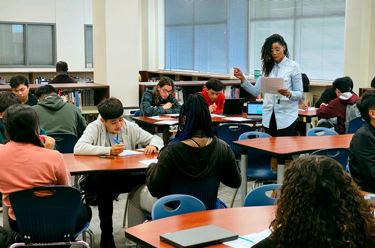 A teacher lectures to students in a library.