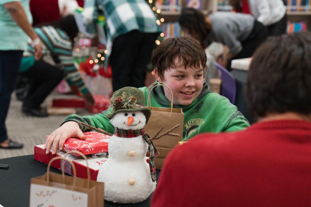 Student smiles holding unwrapped gifts