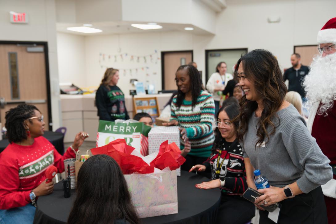 adults smiling as students open gifts