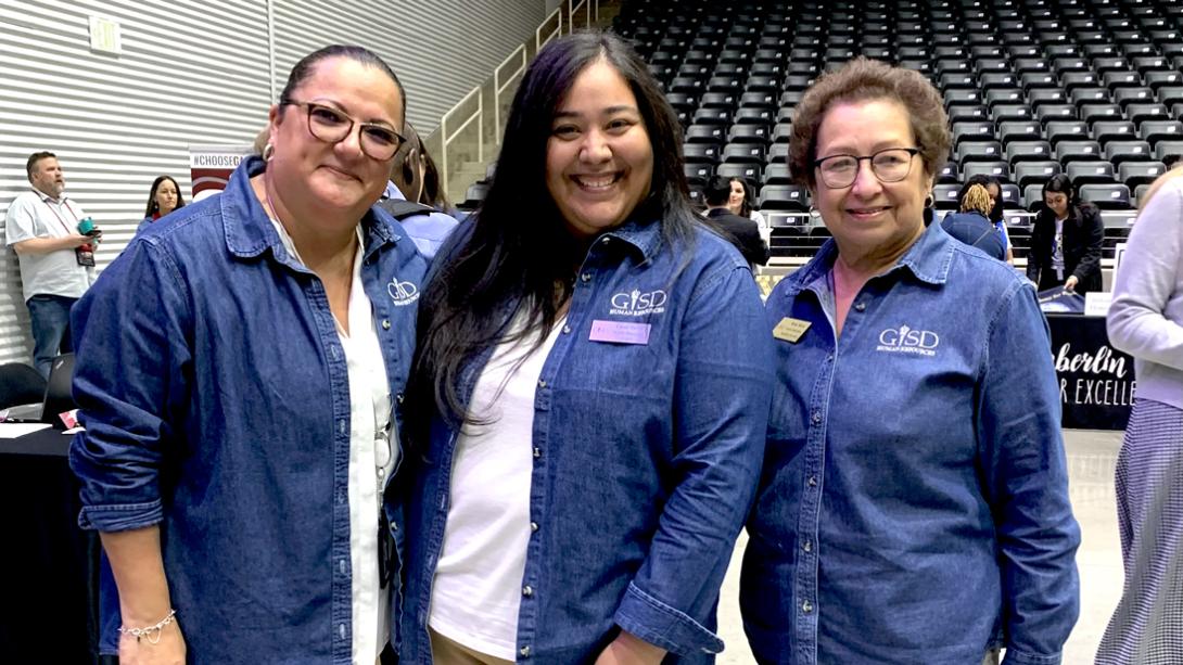 Three women from Human Resources smile at a job fair.