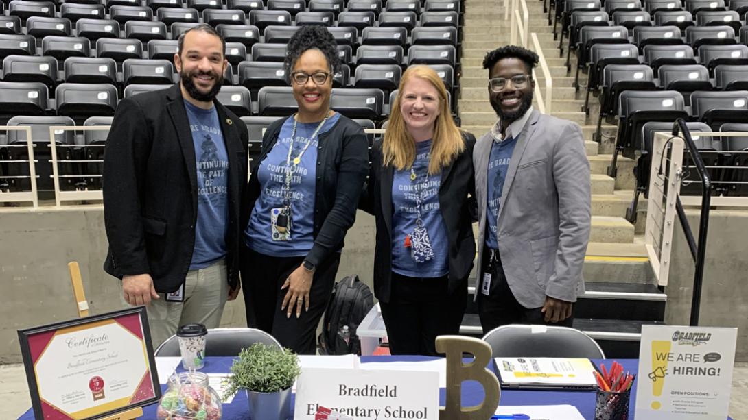 Bradfield Elementary principal and staff smiling at their table during a job fair.