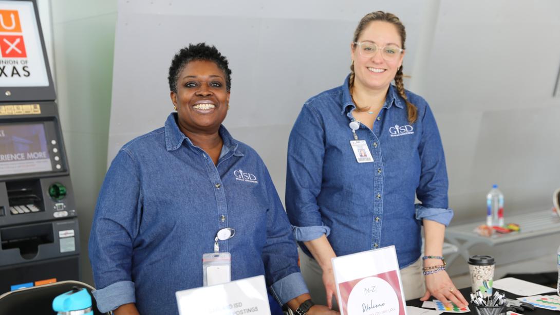 Two HR staff members smile at the check-in table.