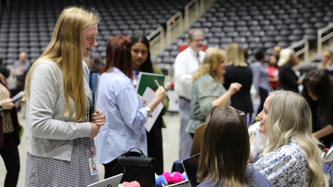 A candidate chats with school staff at a job fair.