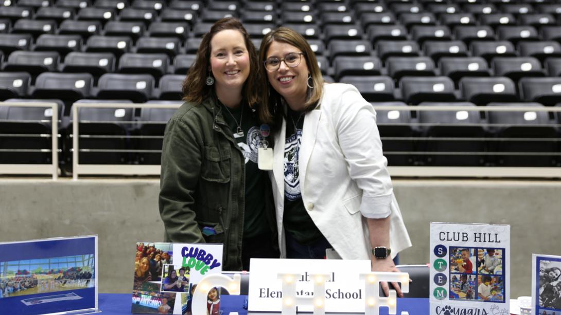 Club Hill staff members smile behind their decorated job fair table.