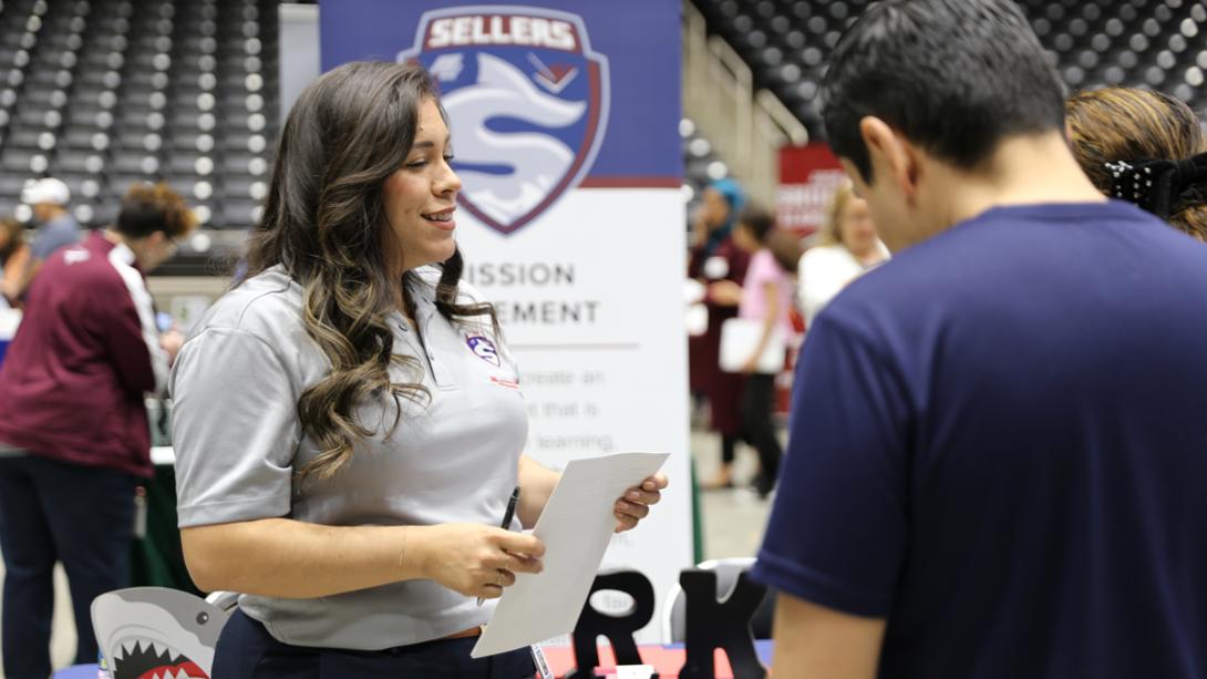 A Sellers staff members smiles while holding a candidate resume.