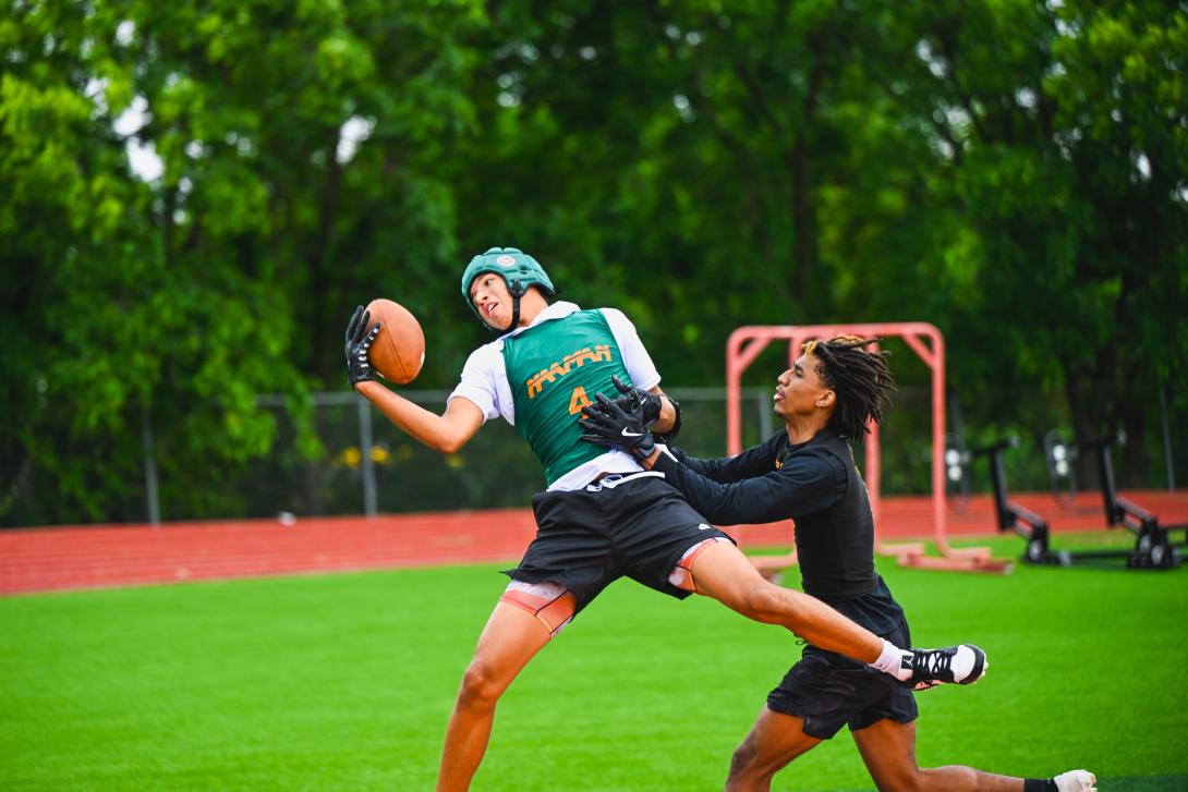 Football player looks over his left shoulder as he catches the ball