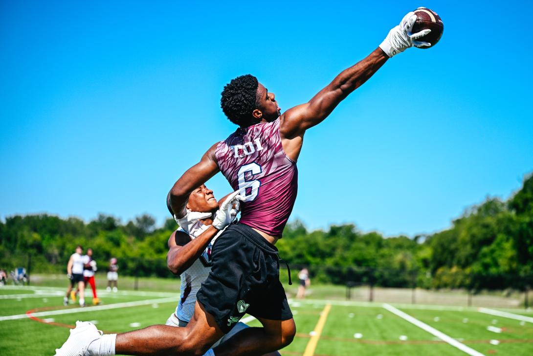 Football player extends his right arm to catch the football