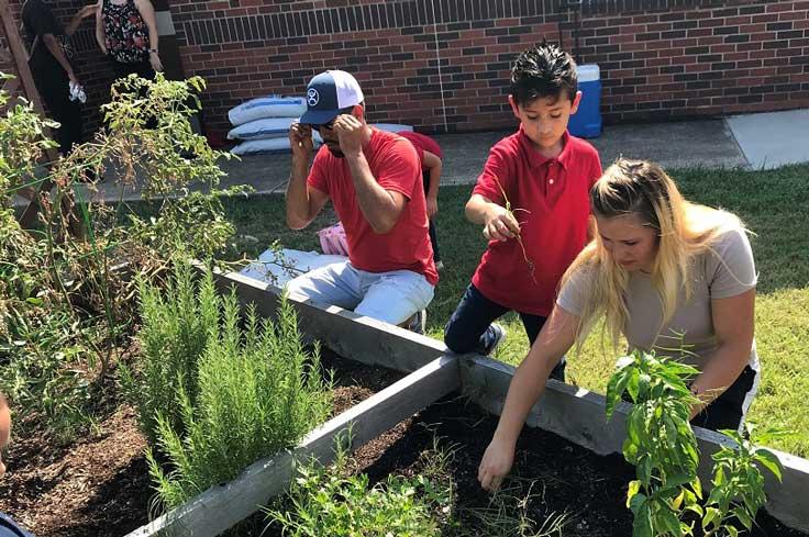 Volunteers working on school garden with a student