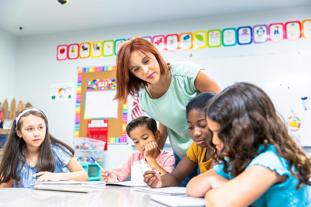 Teacher helping group of students with lesson