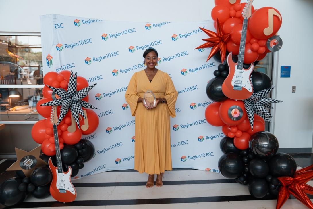 Ashley Ross stands with her plaque in front of a backdrop