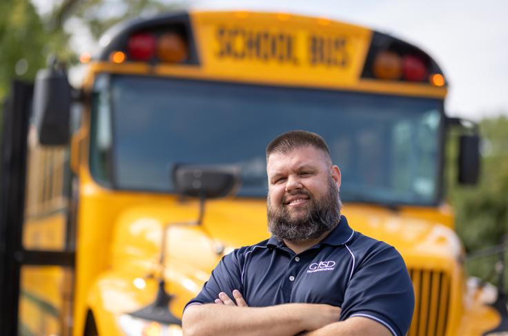 Male bus driver standing in front of bus
