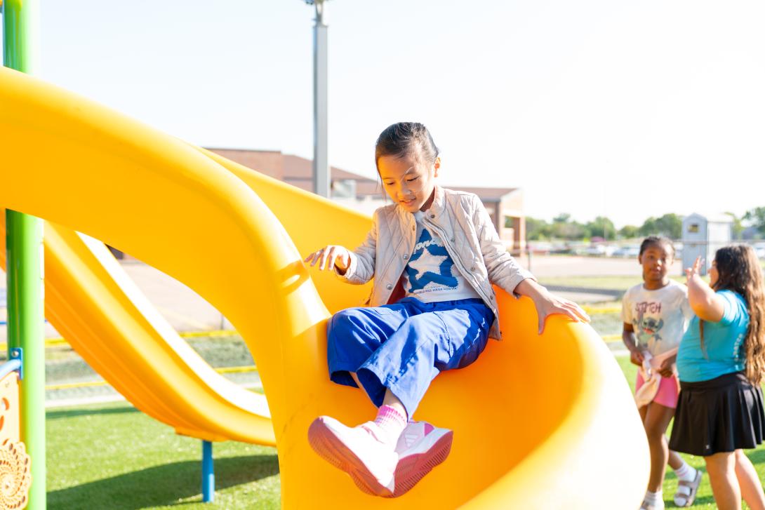 Young girl smiles while going down a slide