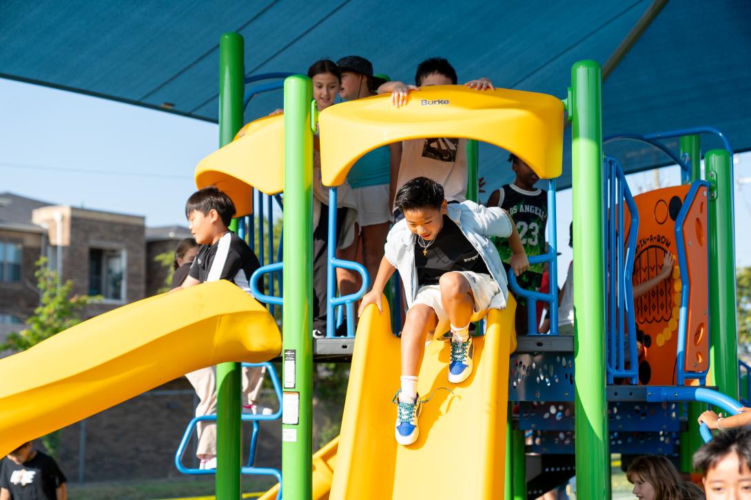 A young student prepares to go down a slide.