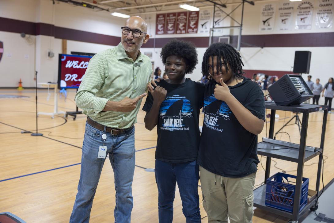One adult and two students pose for the camera