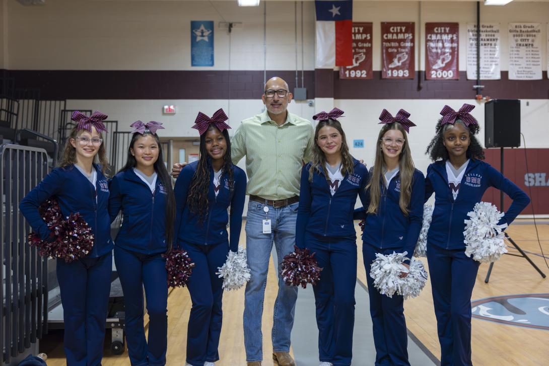 Dr. Lopez poses with a diverse group of middle school cheerleaders